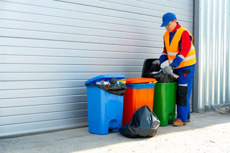 Janitor takes garbage out of trash container outdoors in the street