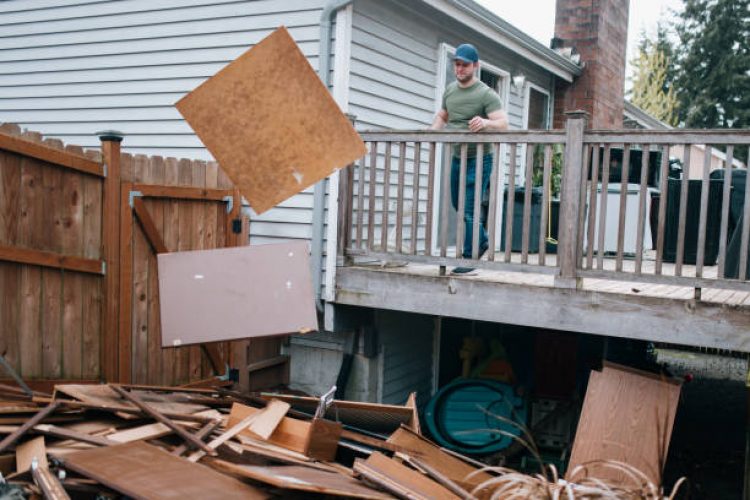 A Caucasian man throws out material into a trash heap from demolition in a house renovation project.
