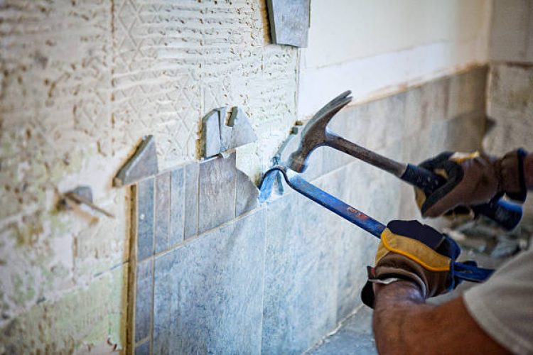 Man removing tile out old kitchen during home renovations.