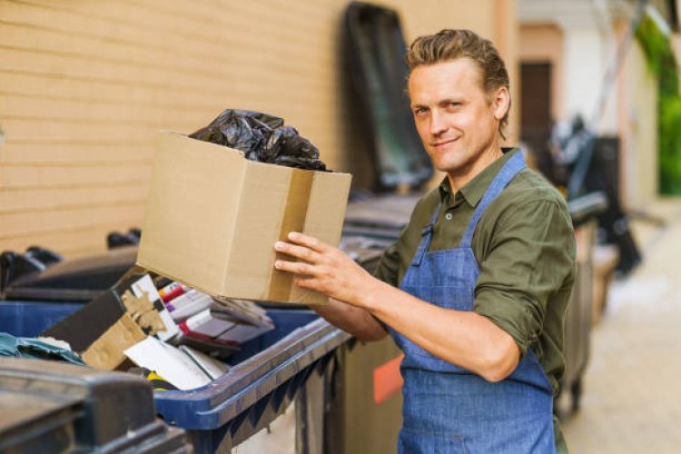 Man sorting garbage before throwing it into trash can. Man, possibly service worker, is engaged in preparation of waste for further utilization.Importance of recycling and sustainability in waste management. . High quality photo