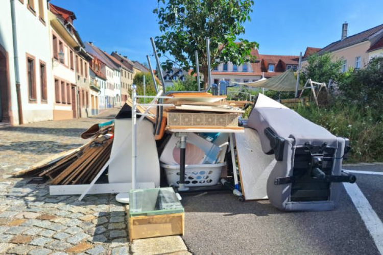 A heap of assorted discarded household items and furniture piled up on a cobblestone street, depicting a bulk waste collection day in an urban environment