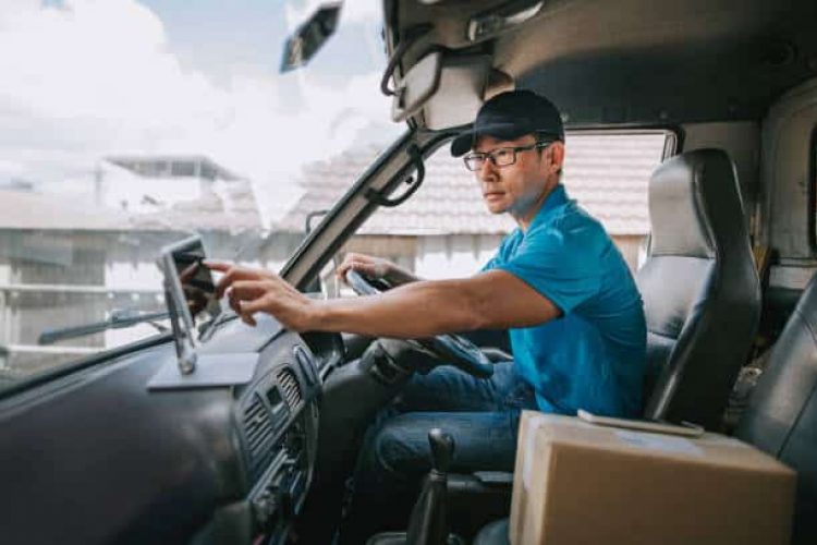 e7 asian chinese mature male delivery person using digital tablet mobile app checking delivery information in driver's seat in delivery van
