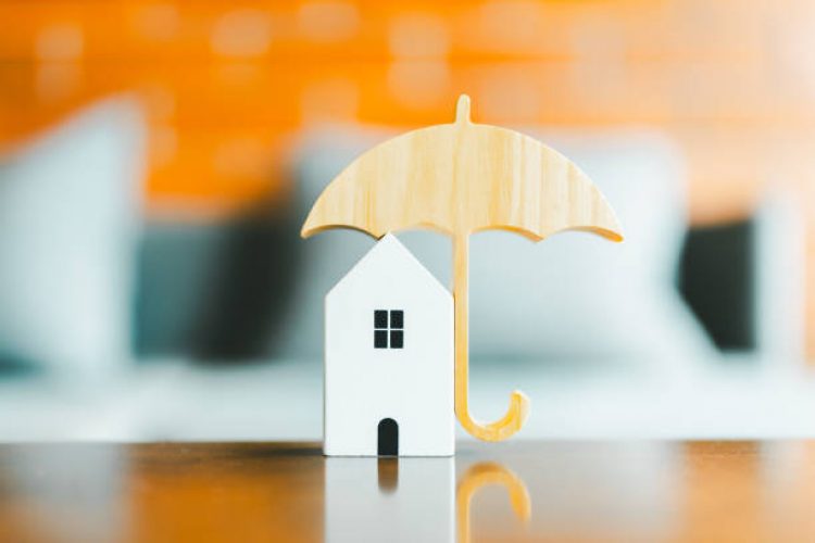 Model of umbrella with house on wooden table concept of the system of insurance savings and Housing insurance against impending loss and fire, building fire insurance concepts.