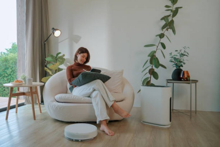 Asian woman working at home while vacuum cleaner and air purifier are working