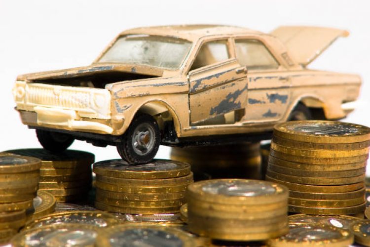 A model of an old car is standing on coins. The concept of expensive maintenance of an old car or its disposal